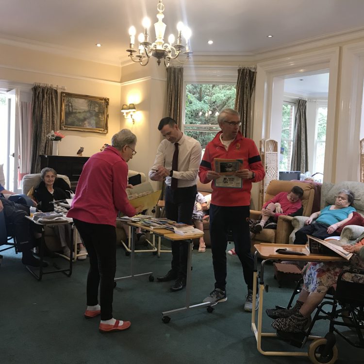 Former Shrewsbury Town players pass round old programmes at Maesbrook Care home during Meadow Memories